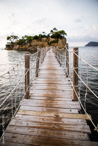 wooden footbridge leading to the small island of Agios Sostis on Zakynthos, Greece, during a sunny summer day © Melinda Nagy