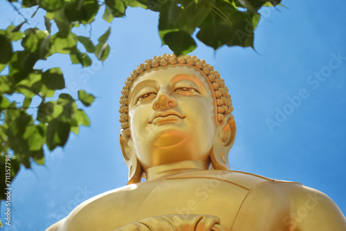Wat Paknam Temple of Thailand Bangkok Huge Golden Buddha with leaves and a blue sky