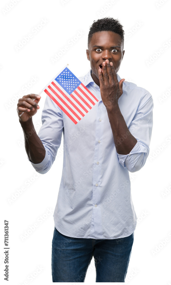 Young african american man holding USA flag cover mouth with hand shocked with shame for mistake, expression of fear, scared in silence, secret concept Young african american man holding USA flag cover mouth with hand shocked with shame for mistake, expression of fear, scared in silence, secret concept
