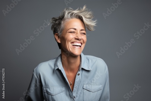 Portrait of a happy middle aged woman laughing and looking up against grey background