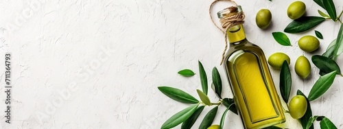 Extra Virgin Olive Oil in a Glass Bottle with Fresh Olives and Green Leaves on a Textured Background. photo