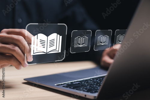 E-library concept. Person use laptop with virtual E-book icons for electronic books online, knowledge base on internet, digital library or e-library. photo