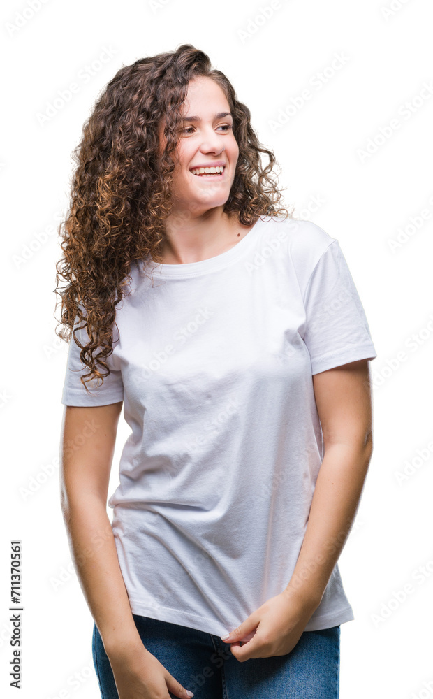 Fototapeta premium Beautiful brunette curly hair young girl wearing casual t-shirt over isolated background looking away to side with smile on face, natural expression. Laughing confident.