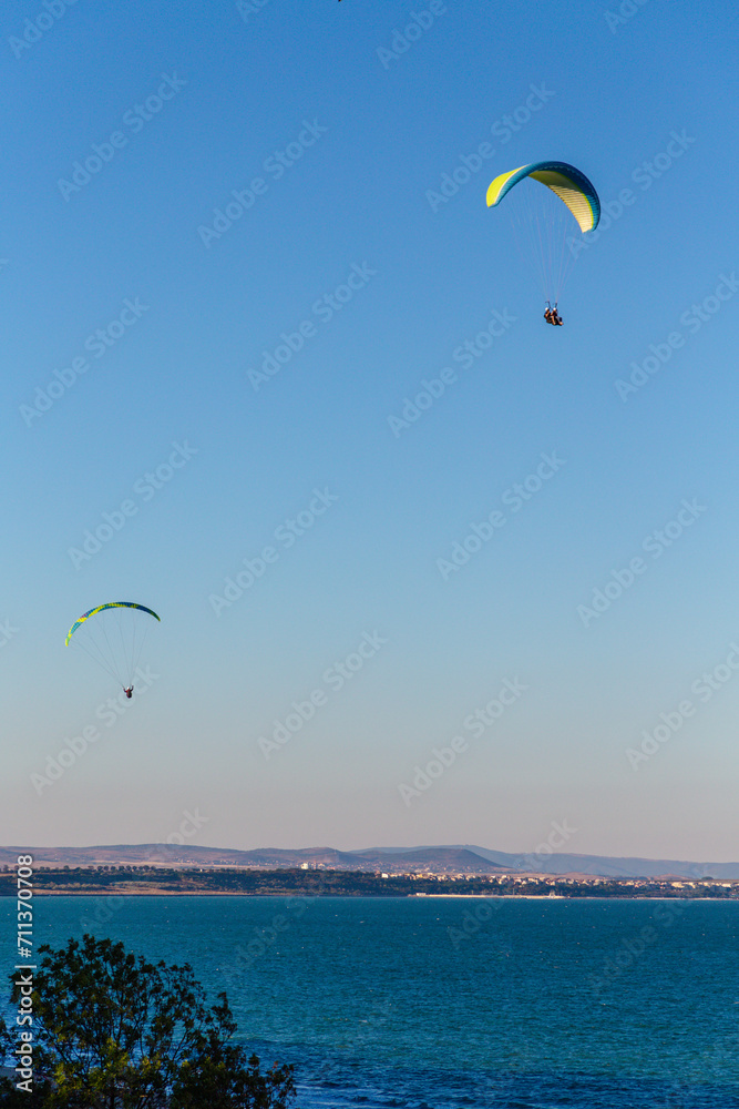 Paraglider flying over the sea coast in blue sky background Paraglider flying over the sea coast in blue sky background