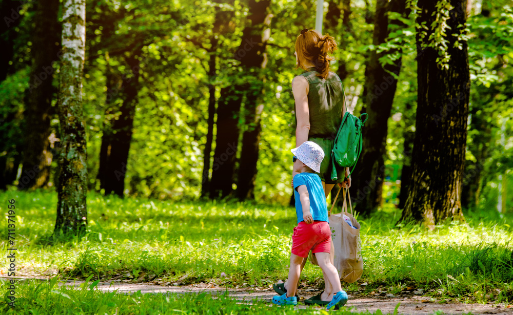 Fototapeta premium A woman and her son are walking in a city park 