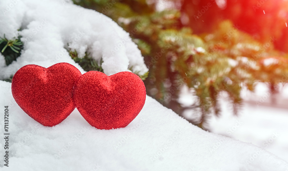 Fototapeta premium Symbol of love hangs on snow-covered spruce 