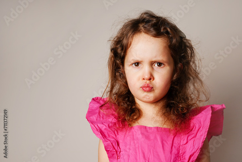 Beautiful angry little child girl looking at you. the child puffed out her cheeks