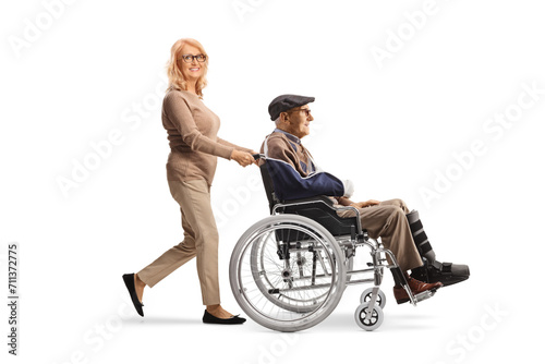 Middle aged woman pushing a senior with a broken arm in a wheelchair
