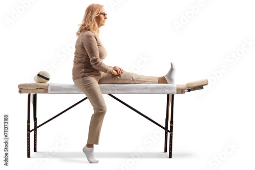 Full length profile shot of a woman sitting on a physical therapy table