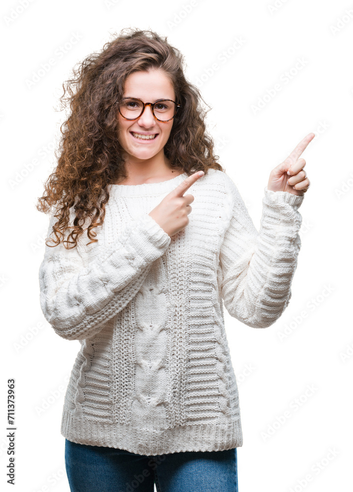 Beautiful brunette curly hair young girl wearing winter sweater over isolated background smiling and looking at the camera pointing with two hands and fingers to the side.