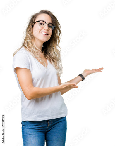 Beautiful young blonde woman wearing glasses over isolated background Inviting to enter smiling natural with open hand