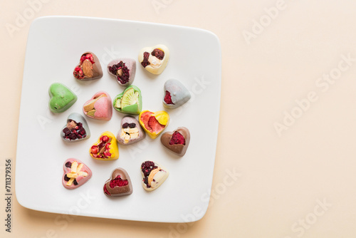 Plate with different chocolate on colored background. Assortment of fine chocolates top view vith copy space Health and obesity concept