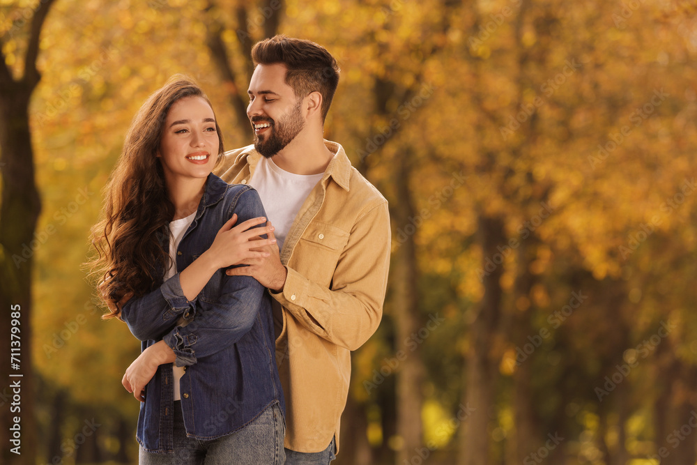 Fototapeta premium Beautiful couple spending time together in autumn park, space for text