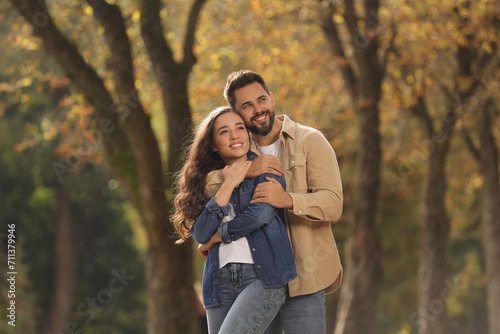 Beautiful young couple hugging in park on autumn day