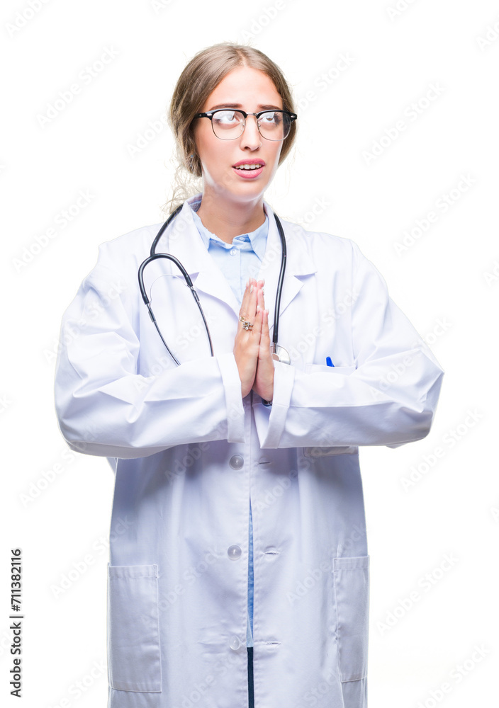 Beautiful young blonde doctor woman wearing medical uniform over isolated background begging and praying with hands together with hope expression on face very emotional and worried. Beautiful young blonde doctor woman wearing medical uniform over isolated background begging and praying with hands together with hope expression on face very emotional and worried.