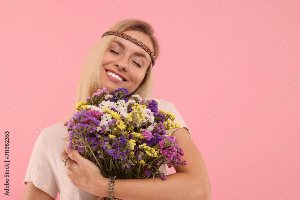 Portrait of smiling hippie woman with bouquet of flowers on pink background. Space for text Portrait of smiling hippie woman with bouquet of flowers on pink background. Space for text