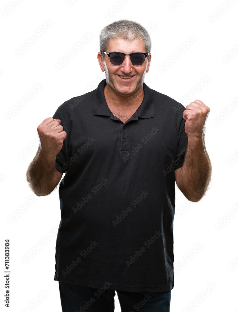 Handsome senior man wearing sunglasses over isolated background very happy and excited doing winner gesture with arms raised, smiling and screaming for success. Celebration concept.