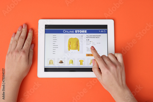 Woman with tablet shopping online on orange background, top view photo