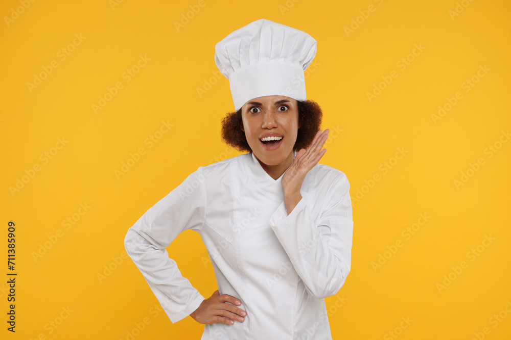 Portrait of emotional female chef in uniform on orange background Portrait of emotional female chef in uniform on orange background