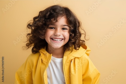 Portrait of a smiling little girl in a yellow raincoat on a yellow background
