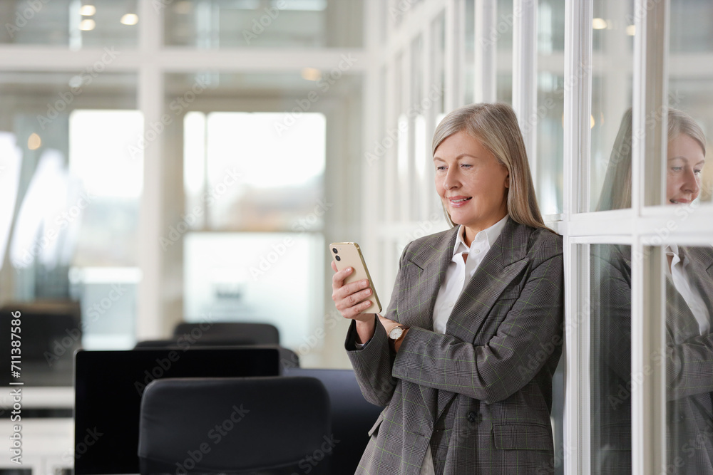 Smiling woman with smartphone in office, space for text. Lawyer, businesswoman, accountant or manager Smiling woman with smartphone in office, space for text. Lawyer, businesswoman, accountant or manager