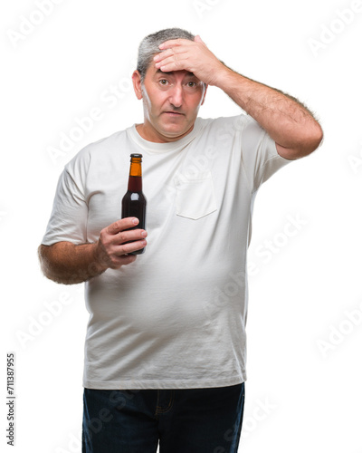 Handsome senior man drinking beer bottle over isolated background stressed with hand on head, shocked with shame and surprise face, angry and frustrated. Fear and upset for mistake.