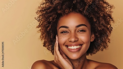 Happy young adult African American woman beauty female model, pretty 20s Black lady with curly hair beautiful face advertising skin care products isolated at beige background. Aesthetic authentic shot