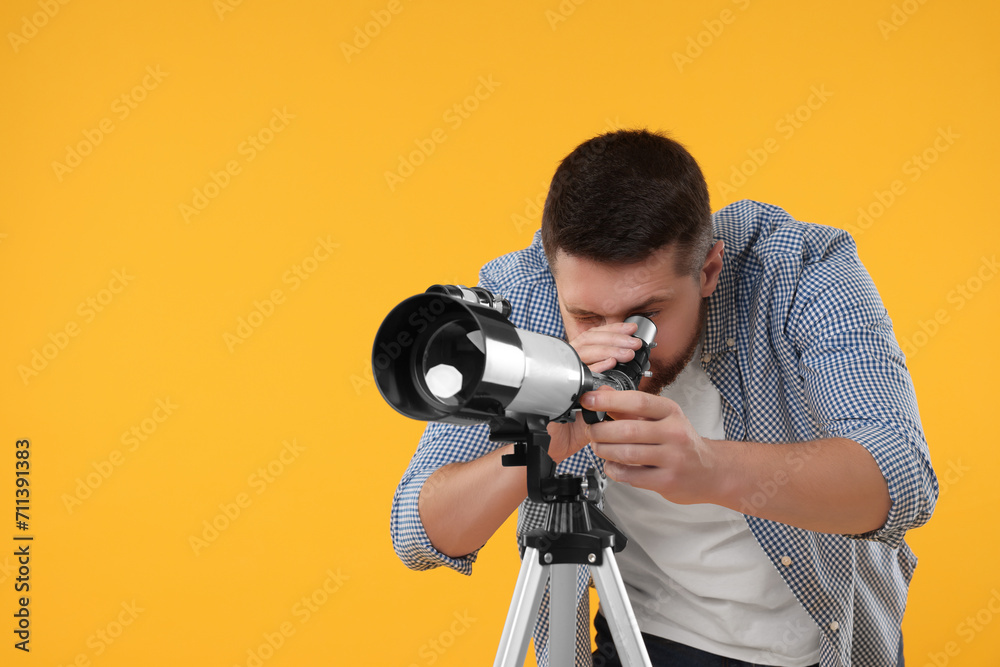 Astronomer looking at stars through telescope on orange background. Space for text