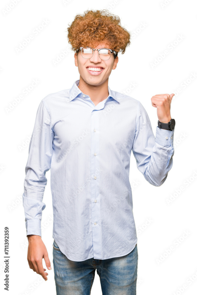 Young handsome business man with afro wearing glasses smiling with happy face looking and pointing to the side with thumb up. Young handsome business man with afro wearing glasses smiling with happy face looking and pointing to the side with thumb up.