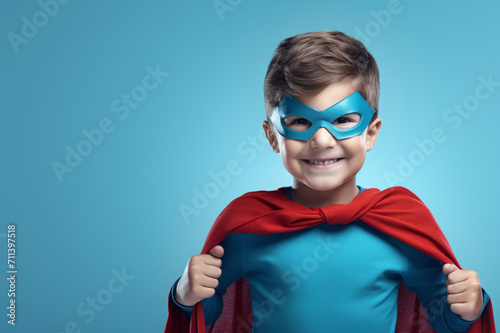 Joyful child in superhero costume on blue background