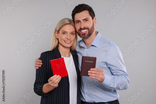 Immigration. Happy couple with passports on gray background photo