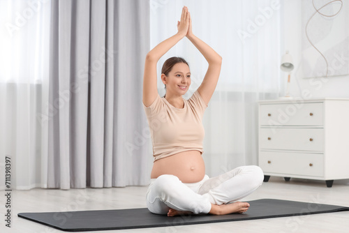 Pregnant woman doing exercises on yoga mat at home