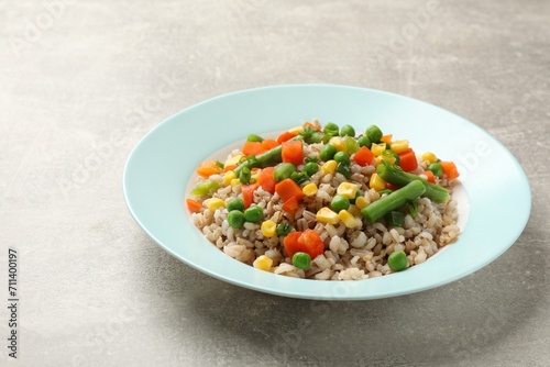 Tasty pearl barley porridge with vegetables on light textured table, closeup