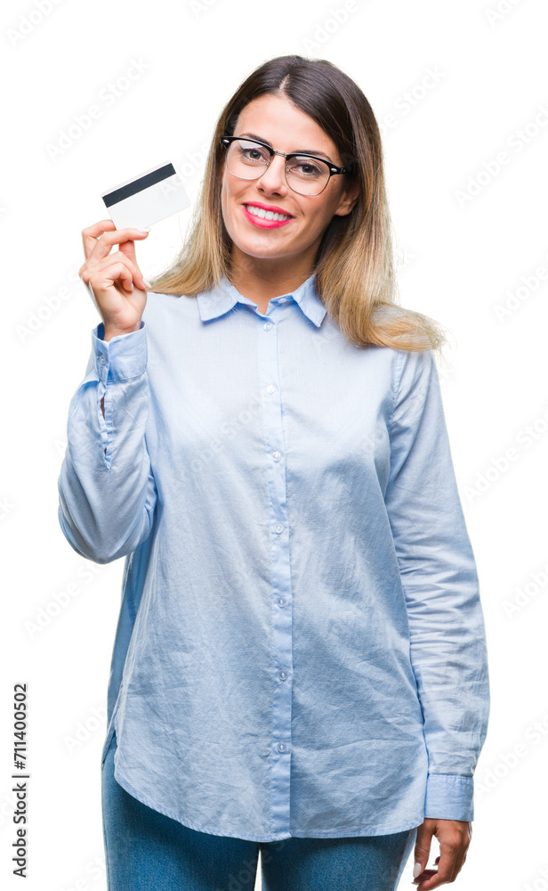 Young beautiful business woman holding credit card over isolated background with a happy face standing and smiling with a confident smile showing teeth Young beautiful business woman holding credit card over isolated background with a happy face standing and smiling with a confident smile showing teeth