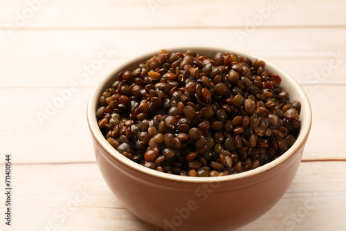 Delicious lentils in bowl on white wooden table, closeup. Space for text