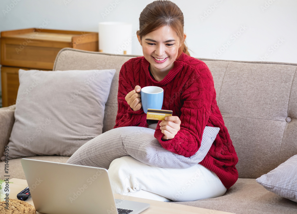 A young Asian woman with a happy smile holds a credit card and uses a smartphone to shop online Online payment concept. A young Asian woman with a happy smile holds a credit card and uses a smartphone to shop online Online payment concept.