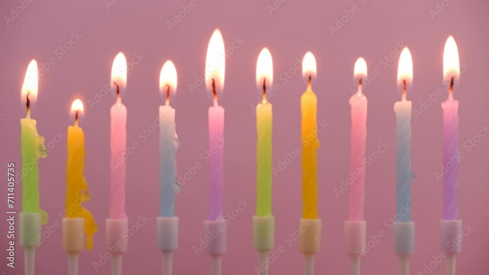 Colorful birthday candles burning on pink background. Colorful birthday candles burning on pink background.