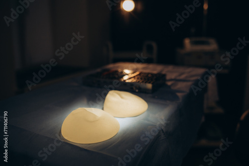Surgical scissors, tweezers, scalpel and silicone breast implant on operating table. Clinic of plastic surgery and breast augmentation and mammoplasty photo