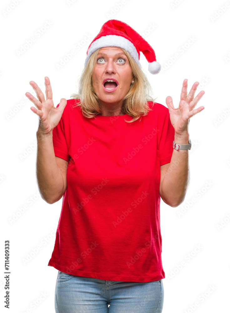 Middle age blonde woman wearing christmas hat over isolated background crazy and mad shouting and yelling with aggressive expression and arms raised. Frustration concept. Middle age blonde woman wearing christmas hat over isolated background crazy and mad shouting and yelling with aggressive expression and arms raised. Frustration concept.