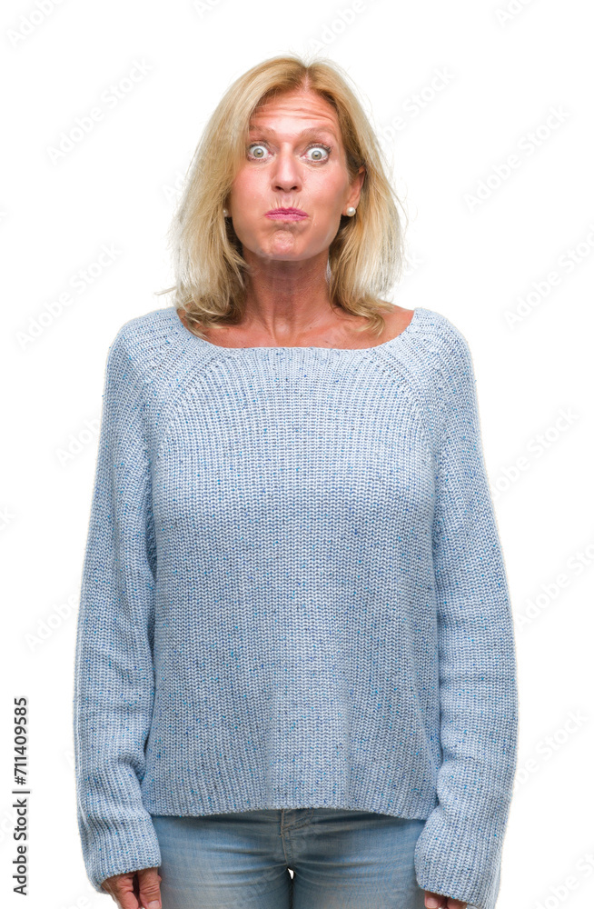 Middle age blonde woman wearing winter sweater over isolated background puffing cheeks with funny face. Mouth inflated with air, crazy expression. Middle age blonde woman wearing winter sweater over isolated background puffing cheeks with funny face. Mouth inflated with air, crazy expression.