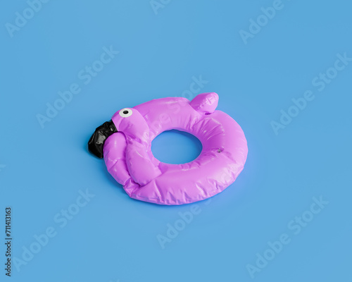 deflated pink flamingo pool float isolated against a solid blue background, summer preparation concept. photo