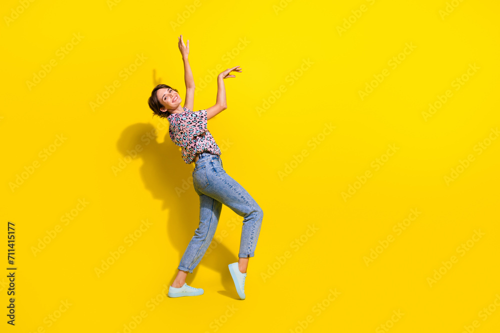 Full length profile portrait of cheerful lovely person raise arms dance rejoice empty space isolated on yellow color background