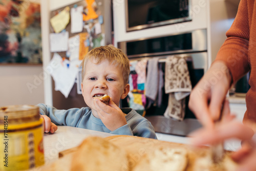 Boy eating bread while parent slices loaf photo