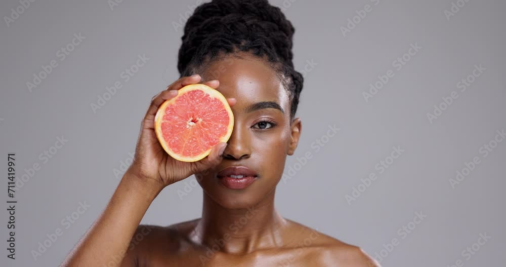 Beauty, face and woman with grapefruit in studio for vitamin c benefits, detox and glow on grey background. Portrait, serious african model and citrus fruits for skincare, sustainability or nutrition
