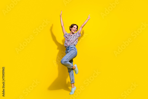 Full length photo of carefree gorgeous person raise hands rejoice dancing empty space isolated on yellow color background