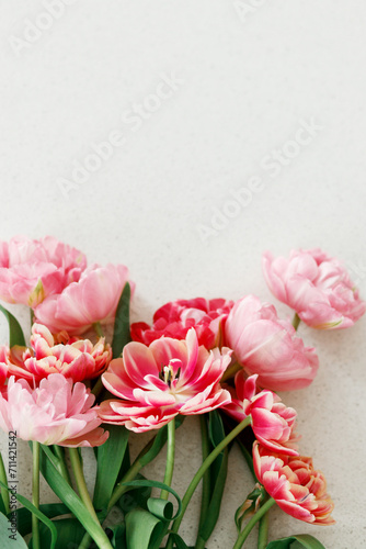 Fototapeta Naklejka Na Ścianę i Meble -  Modern tulips flat lay on grey stone background. Happy Valentines day and happy mother's day bouquet. Stylish beautiful floral wallpaper with space for text. Tender red and pink flowers banner