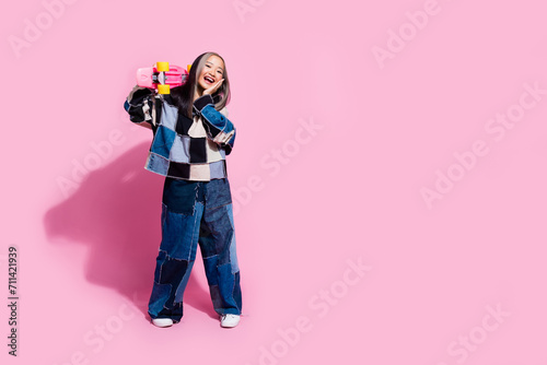 Full length photo of nice adorable youngster wear oversize sweatshirt hold skateboard palm on cheek isolated on pink color background
