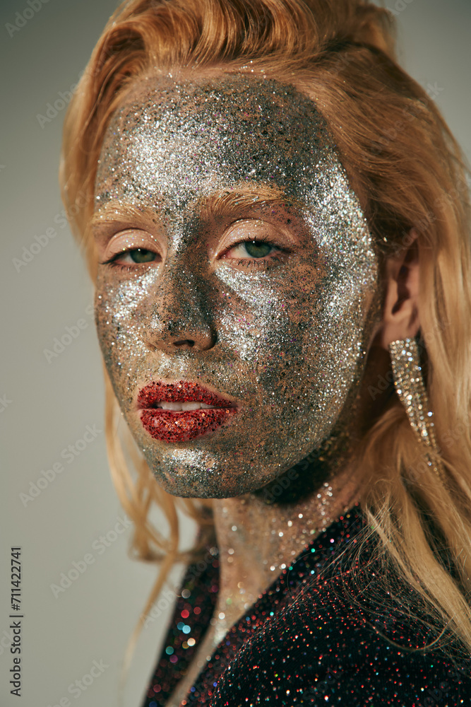 portrait, pretty woman with green eyes and glitter all over body and face posing on grey backdrop portrait, pretty woman with green eyes and glitter all over body and face posing on grey backdrop