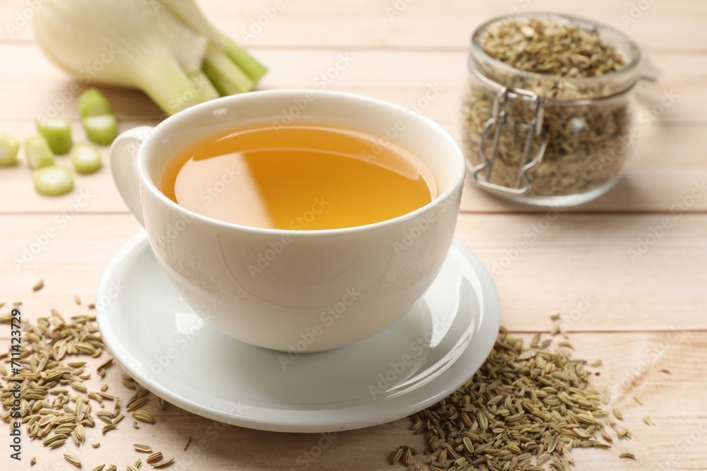 Fennel tea in cup, seeds and fresh vegetable on light wooden table, closeup Fennel tea in cup, seeds and fresh vegetable on light wooden table, closeup