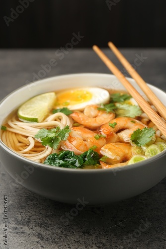 Delicious ramen with shrimps and chopsticks on grey table, closeup. Noodle soup